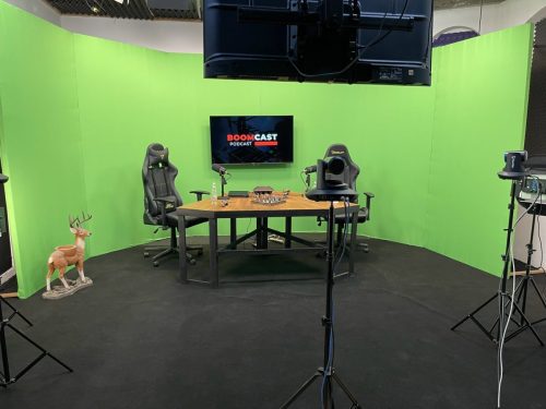 Estudio de grabación de podcast con fondo y suelo Full Chroma Key verde, cámara profesional y mesa de set custom.