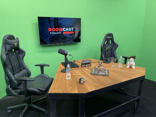 Estudio de grabación de podcast con fondo Chroma Key verde, mesa custom de madera y sillas ergonómicas, listo para la producción de video y contenido digital.