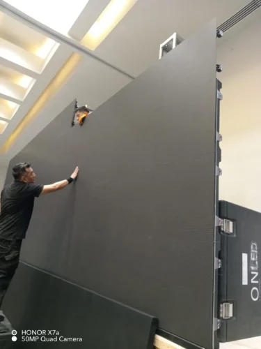 Técnico especialista realizando la instalación, montaje y calibración de una pantalla LED gigante (Video Wall) para evento corporativo.