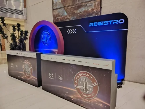Mueble de registro personalizado para evento corporativo con iluminación LED azul y diseño de marca (branding) en el mostrador.