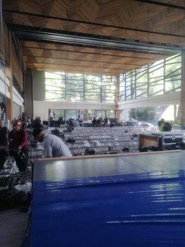 Técnicos ensamblando estructuras truss de aluminio en el suelo de un salón de eventos amplio con ventanales.