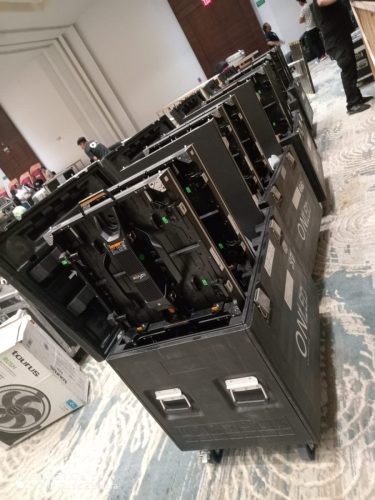 Fila de estuches de transporte tipo flight case abiertos conteniendo módulos de pantalla LED listos para su montaje en un evento.